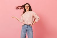 cute-girl-playful-mood-posing-pink-background-young-brunette-knitted-sweater-plays-hair
